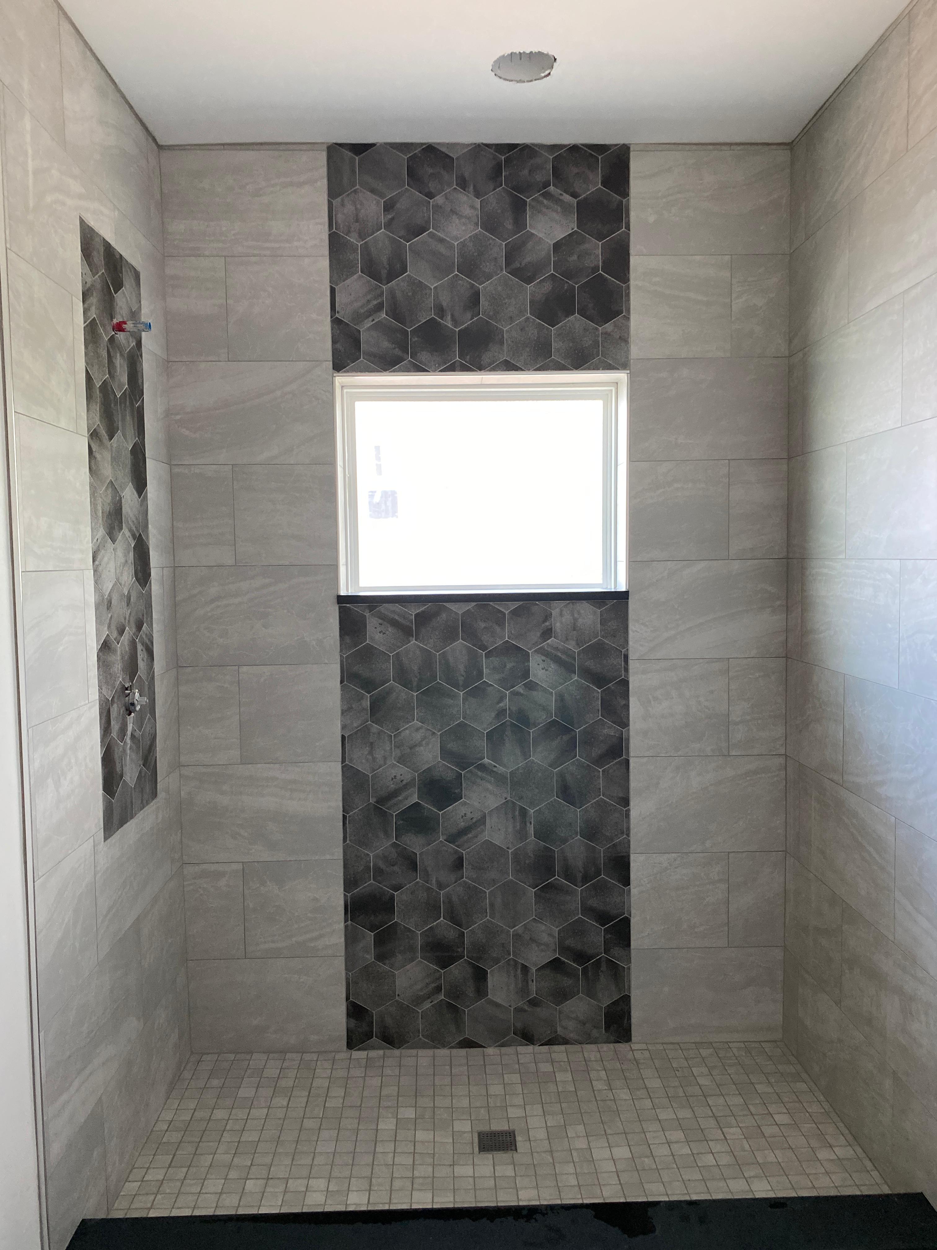 Double vanity wall with arched mirrors and coordinated lighting in the finished primary bathroom.