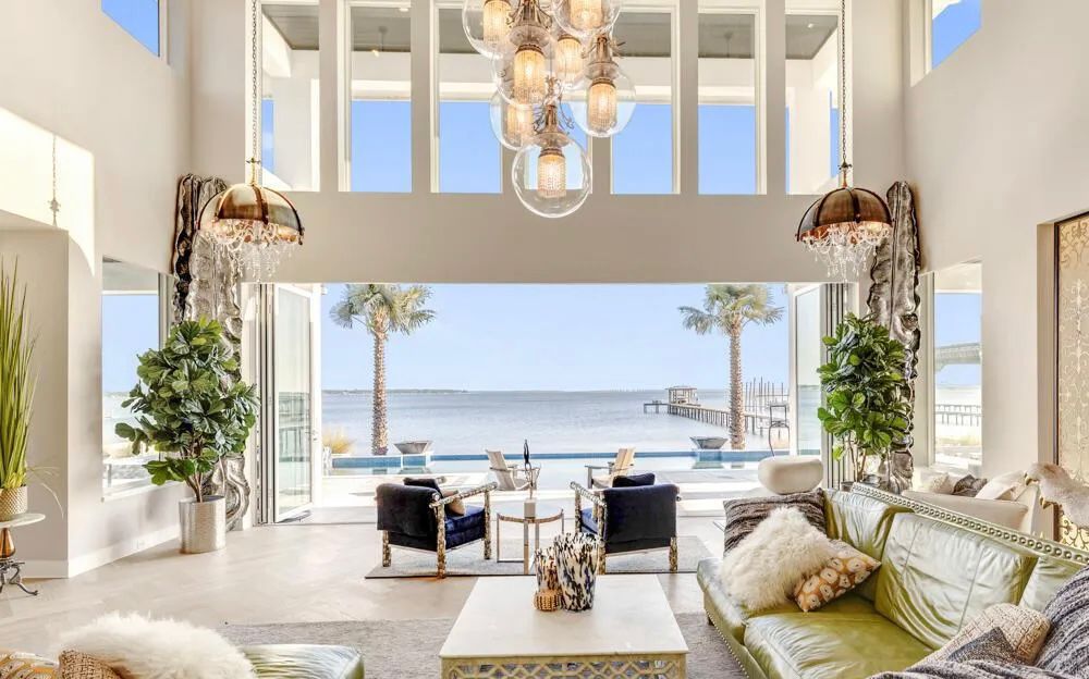 Double-height great room with waterfront view framed by dramatic lighting.