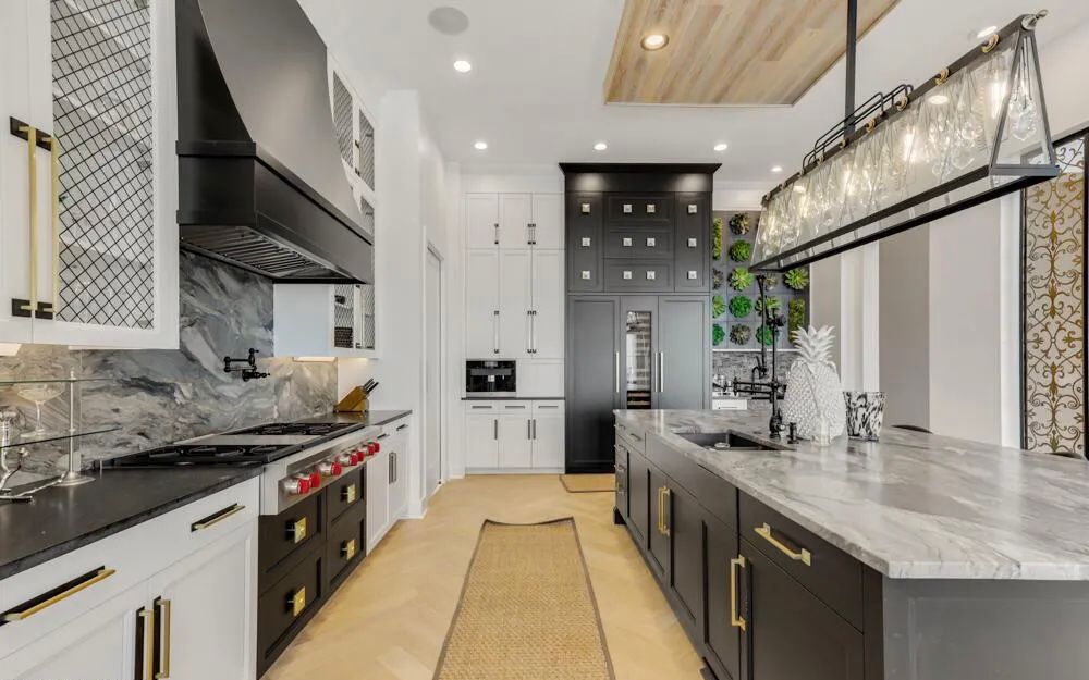 Kitchen perspective showing island seating, slab surfaces, and custom lighting over the prep zone.
