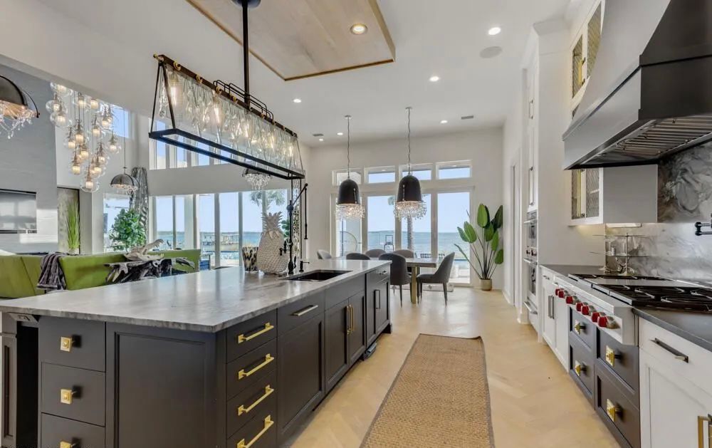 Kitchen with dark island, marble surfaces, and water view beyond the dining area.