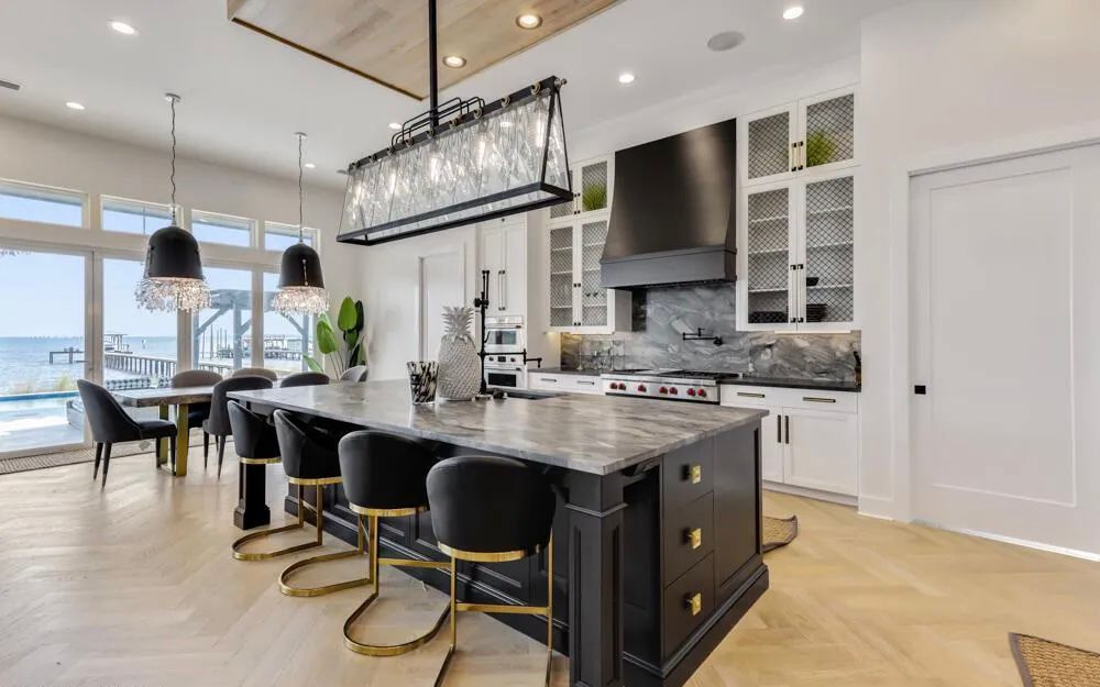Open kitchen with white cabinetry, dark island, and water view beyond the main living area.