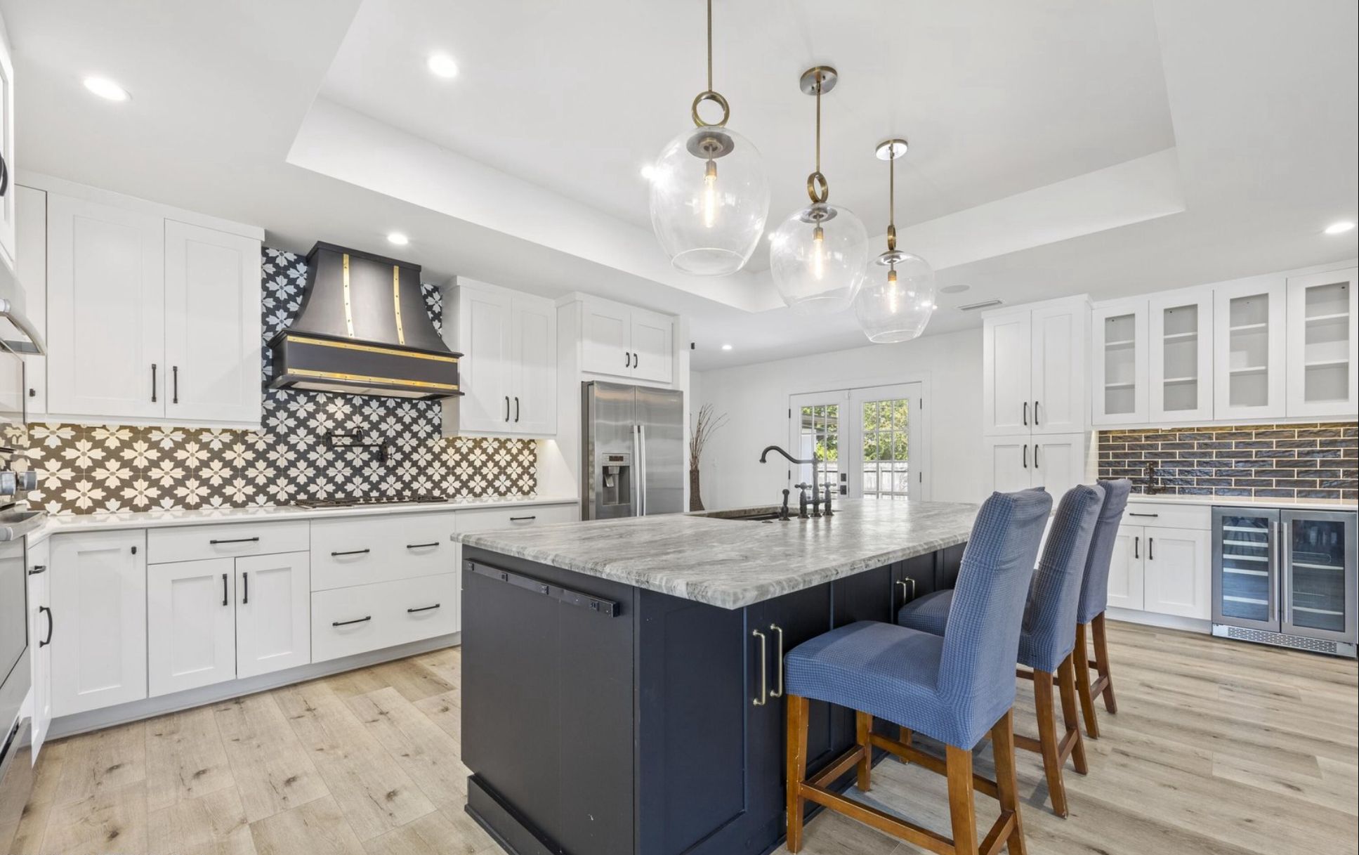 Kitchen view across the navy island toward the hood wall and pendant lighting.