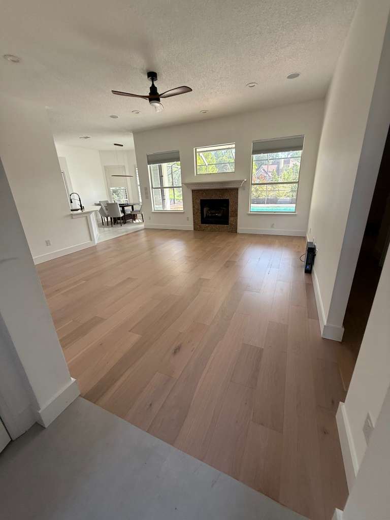 Great room with fireplace and wide-plank flooring leading toward the kitchen.