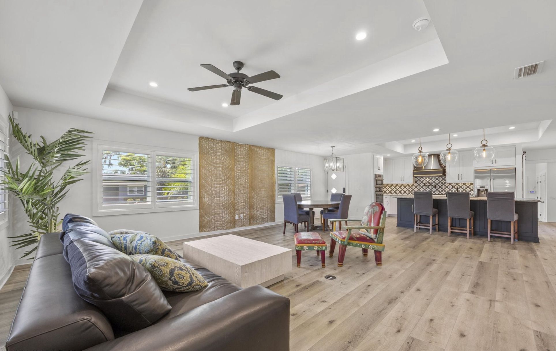 Open-plan living area flowing into a renovated kitchen with navy island and wide-plank flooring.