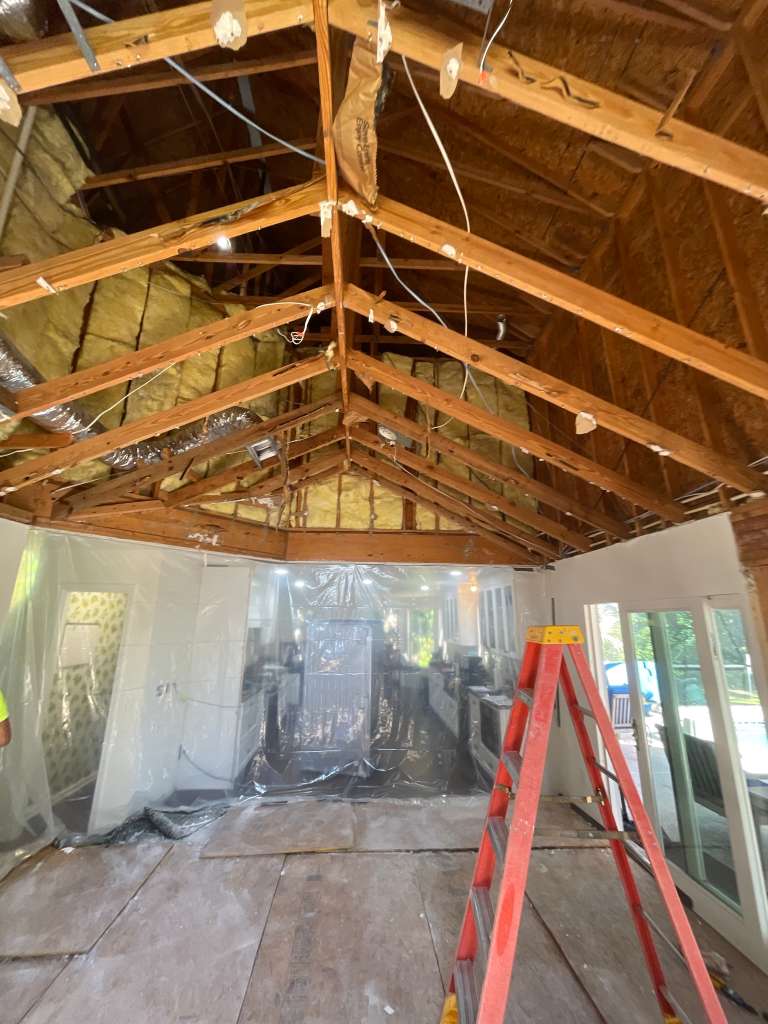 Framing in progress for a residential addition with new window openings and structural tie-ins.
